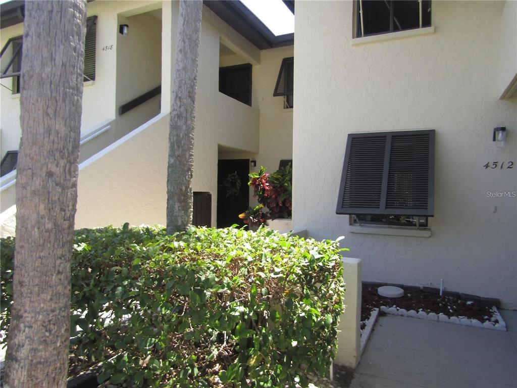 An exterior view of a multi-story residential building with beige stucco walls and dark shutters — 4516 LONGWATER UNIT 29, SARASOTA, FL