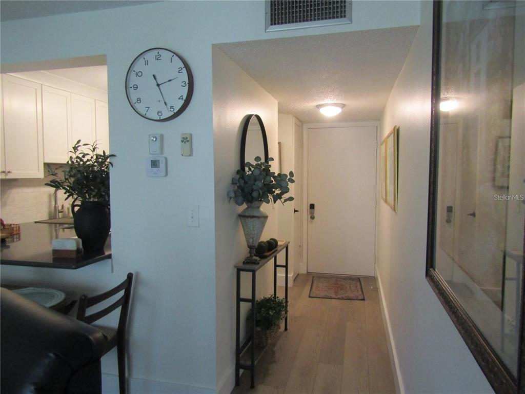 An entryway features a console table, a wall clock, and a view into a kitchen — 4516 LONGWATER UNIT 29, SARASOTA, FL