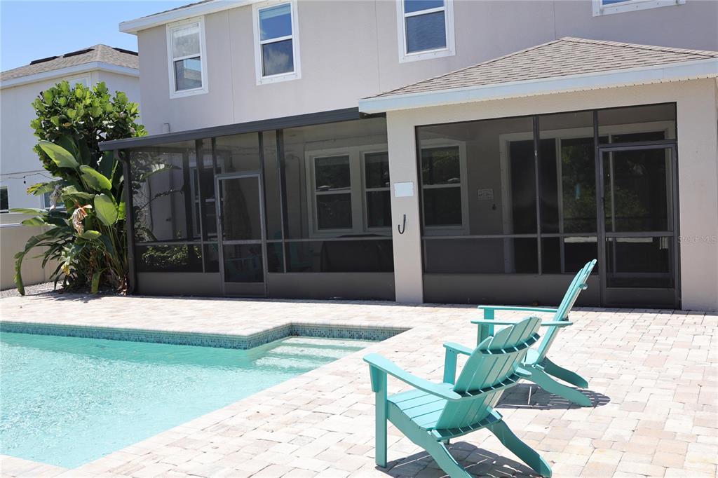 A backyard features a swimming pool, two turquoise chairs, and a screened-in patio area — 5002 JACKEL CHASE DRIVE, WIMAUMA, FL