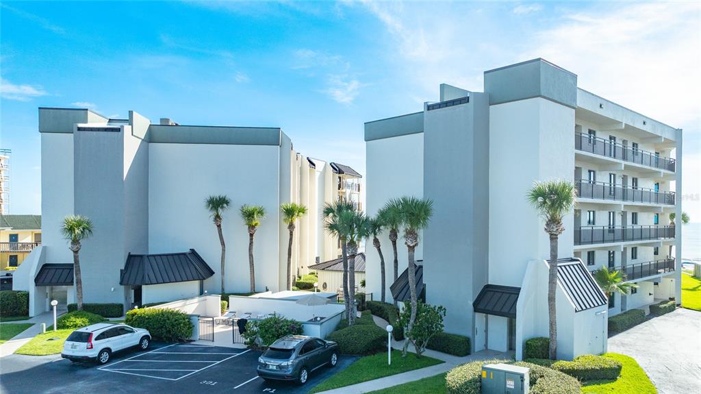 A multi-story apartment building with a parking lot and palm trees in the foreground — 1275 OCEAN SHORE BOULEVARD UNIT P3, ORMOND BEACH, FL