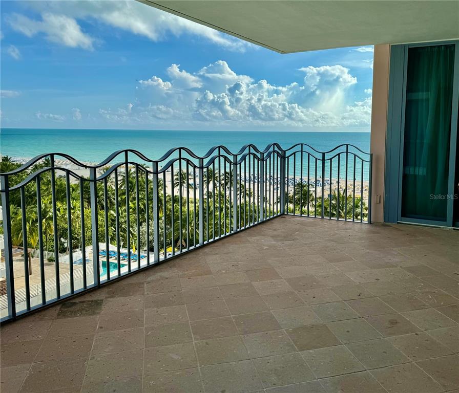A tiled balcony with a decorative metal railing overlooks a beach and the ocean — 1500 OCEAN DRIVE UNIT 905, MIAMI BEACH, FL