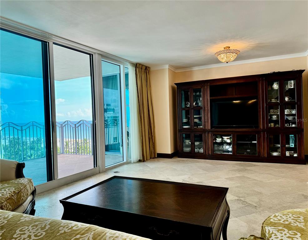 A living room features a large wooden entertainment center, tile flooring, and a balcony with ocean views — 1500 OCEAN DRIVE UNIT 905, MIAMI BEACH, FL