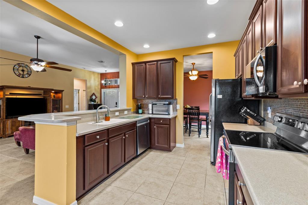 A kitchen with dark wood cabinets, light countertops, and tile flooring, open to a living area — 2617 BRIGHTSIDE COURT, CAPE CORAL, FL