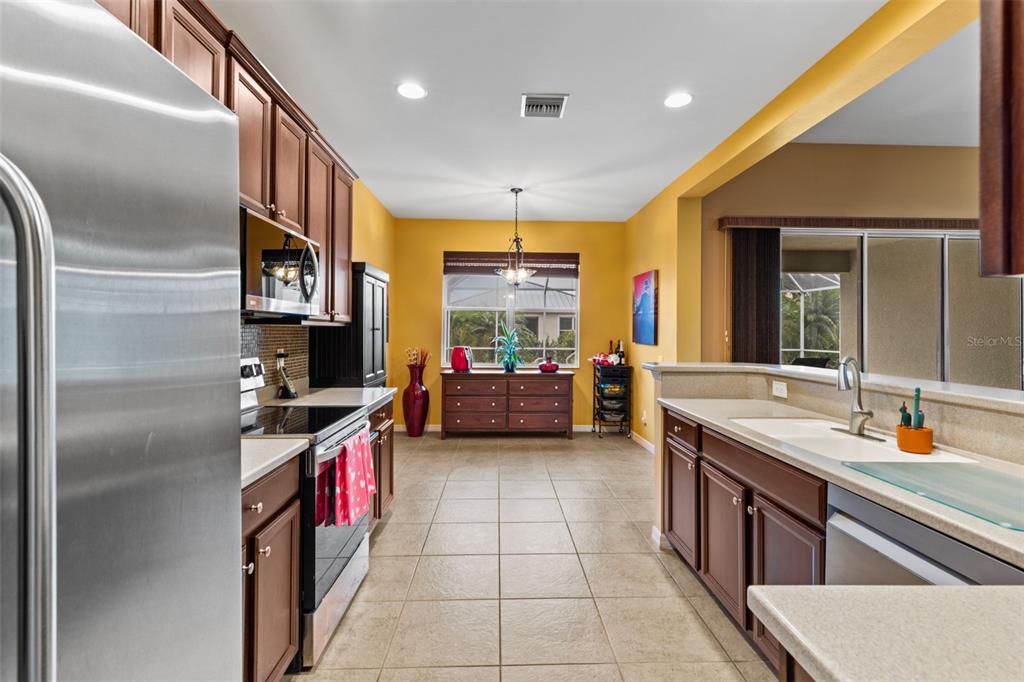 A kitchen with wood cabinets, stainless steel appliances, tile flooring, and yellow walls — 2617 BRIGHTSIDE COURT, CAPE CORAL, FL