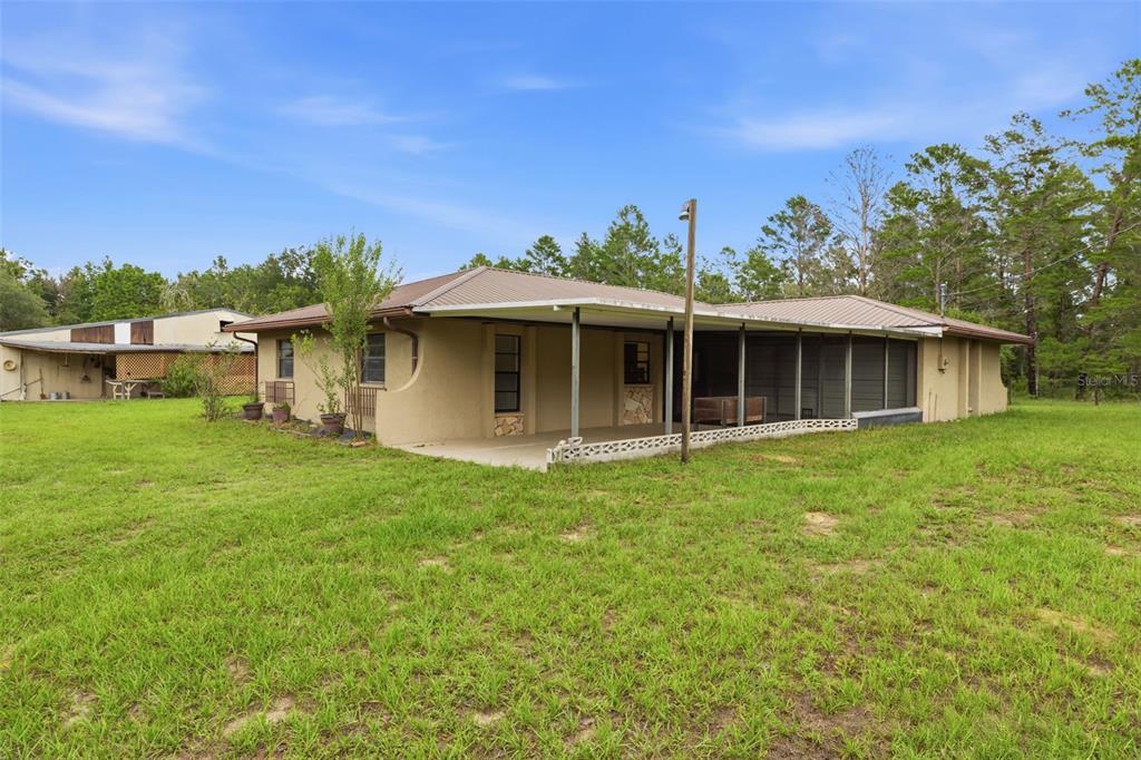 A gravel driveway leads to a single-story house behind a wire fence and gate — 14499 SANDY DRIVE, BROOKSVILLE, FL