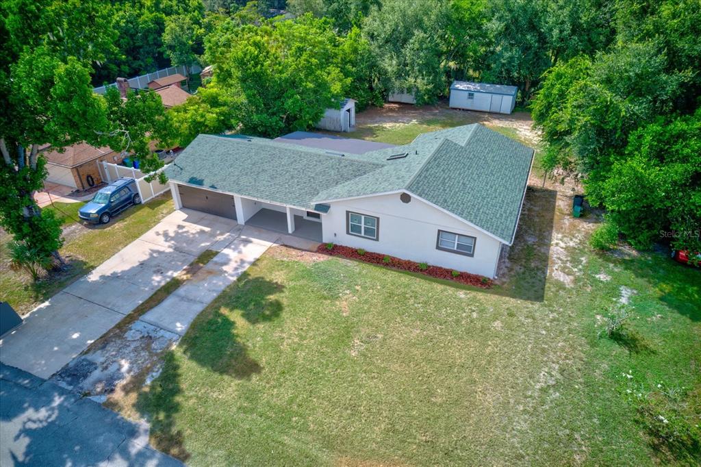 An aerial view shows a single-story house with a green roof, white siding, and driveway — 47 DAHLIA DRIVE, DEBARY, FL