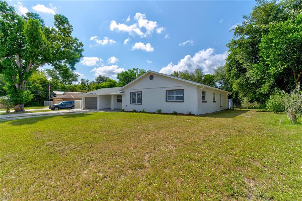 A single-story house with a white exterior, a carport, and a large front lawn — 47 DAHLIA DRIVE, DEBARY, FL
