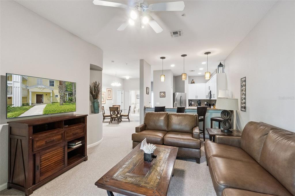A living room with brown leather sofas, a wooden coffee table, and an open kitchen — 106 LUCAYA LOOP, DAVENPORT, FL