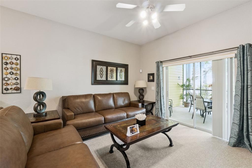 A living room features brown leather sofas, a coffee table, and a sliding glass door — 106 LUCAYA LOOP, DAVENPORT, FL
