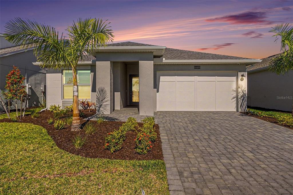 A single-story house with a gray stucco exterior, a two-car garage, and a paved driveway — 44489 PANTHER DRIVE, PUNTA GORDA, FL