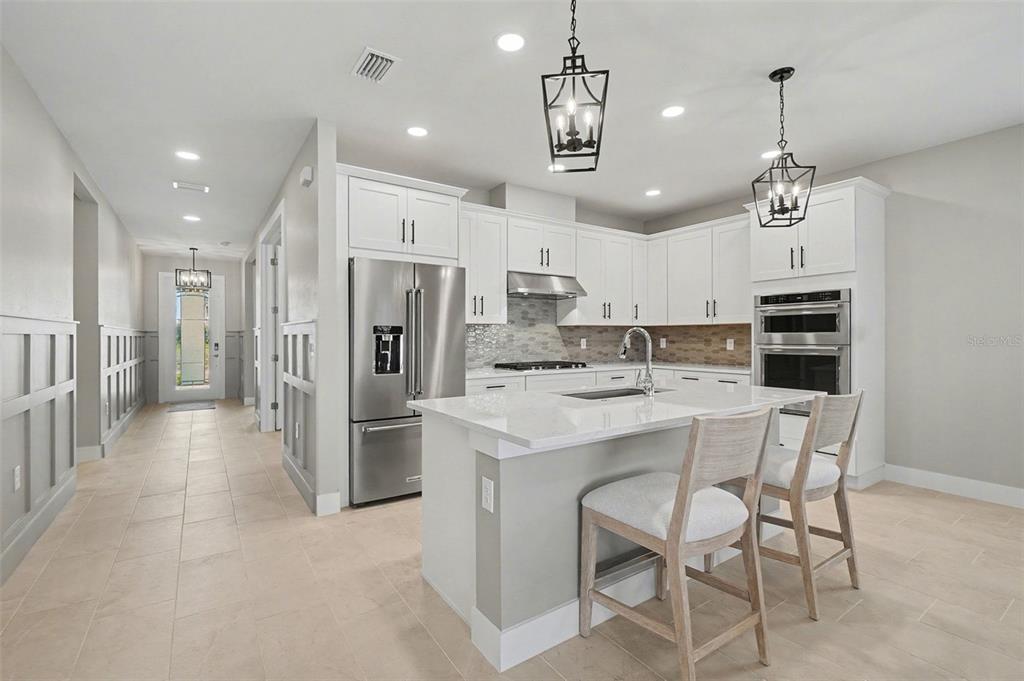 A modern kitchen features white cabinetry, stainless steel appliances, a center island, and pendant lighting — 44489 PANTHER DRIVE, PUNTA GORDA, FL