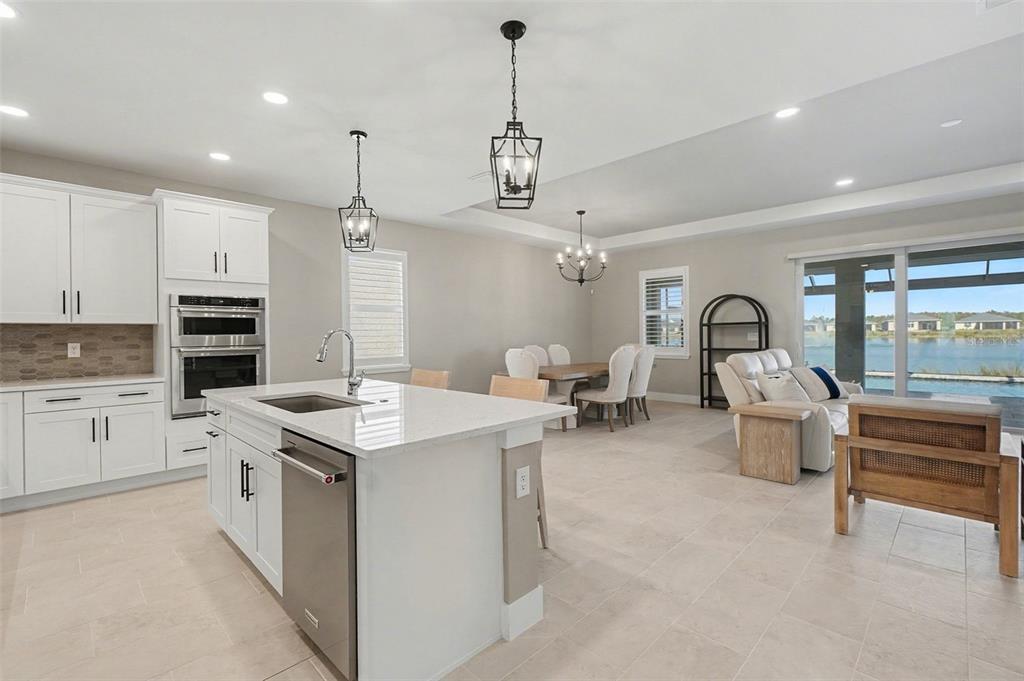 A bright open-concept kitchen and dining area with white cabinetry, a central island, and tile flooring — 44489 PANTHER DRIVE, PUNTA GORDA, FL