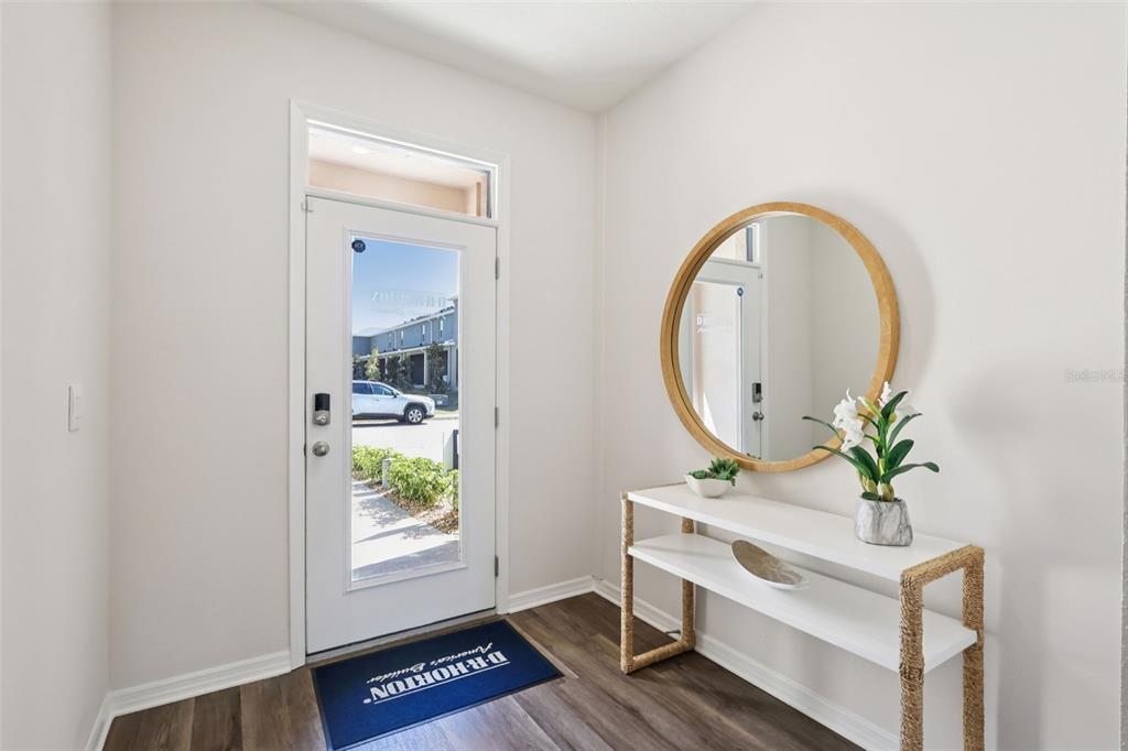An entryway features a white front door, a round mirror, and a white console table — 2765 GLADIOLA ROAD, WINTER HAVEN, FL