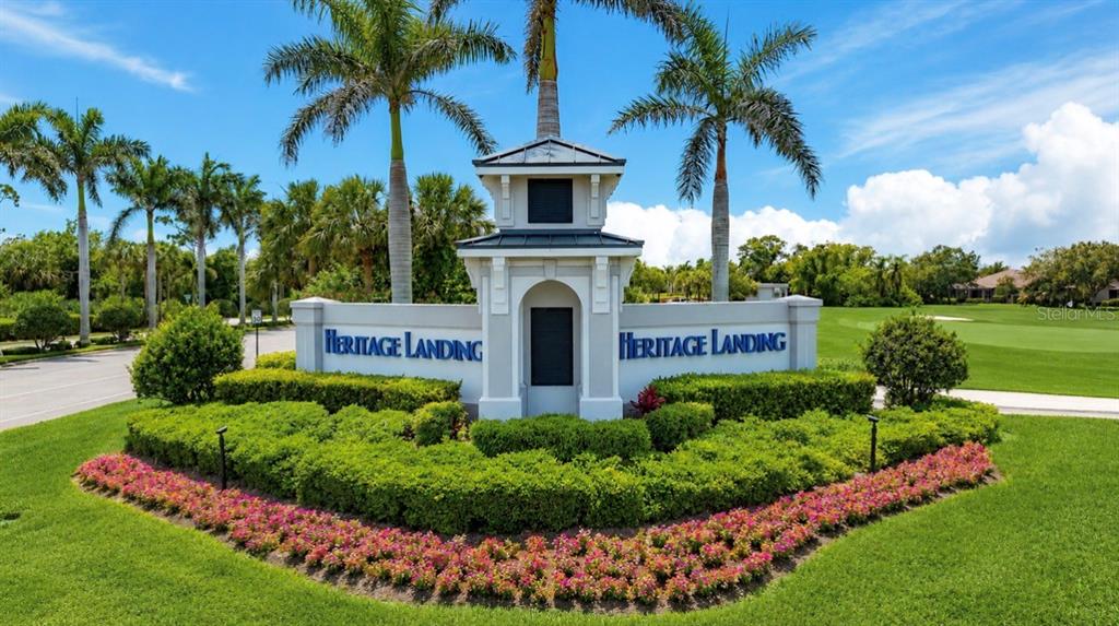 A stone monument sign for Heritage Landing sits in a landscaped garden with palm trees — 14191 HERITAGE LANDING BOULEVARD UNIT 1214, PUNTA GORDA, FL