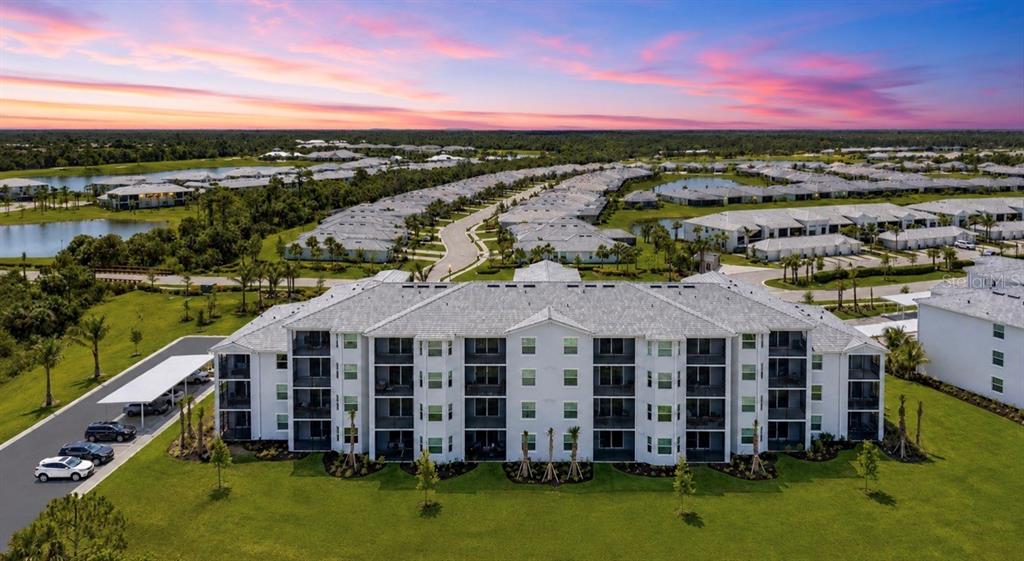 An aerial view shows a multi-story apartment building with a gray roof and surrounding landscaping — 14191 HERITAGE LANDING BOULEVARD UNIT 1214, PUNTA GORDA, FL
