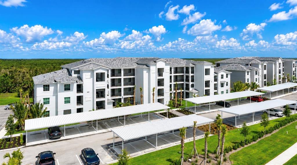 An aerial view of a multi-story apartment complex with covered parking structures and landscaped grounds — 14191 HERITAGE LANDING BOULEVARD UNIT 1214, PUNTA GORDA, FL