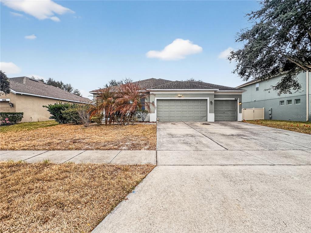 A single-story house with a three-car garage and a dry, brown front lawn — 3497 BUNCHBERRY WAY, OCOEE, FL