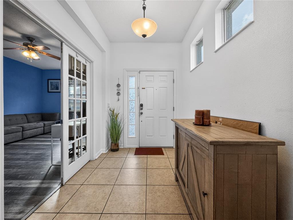 An entryway features tile flooring, a wooden console table, a white front door, and French doors — 3497 BUNCHBERRY WAY, OCOEE, FL