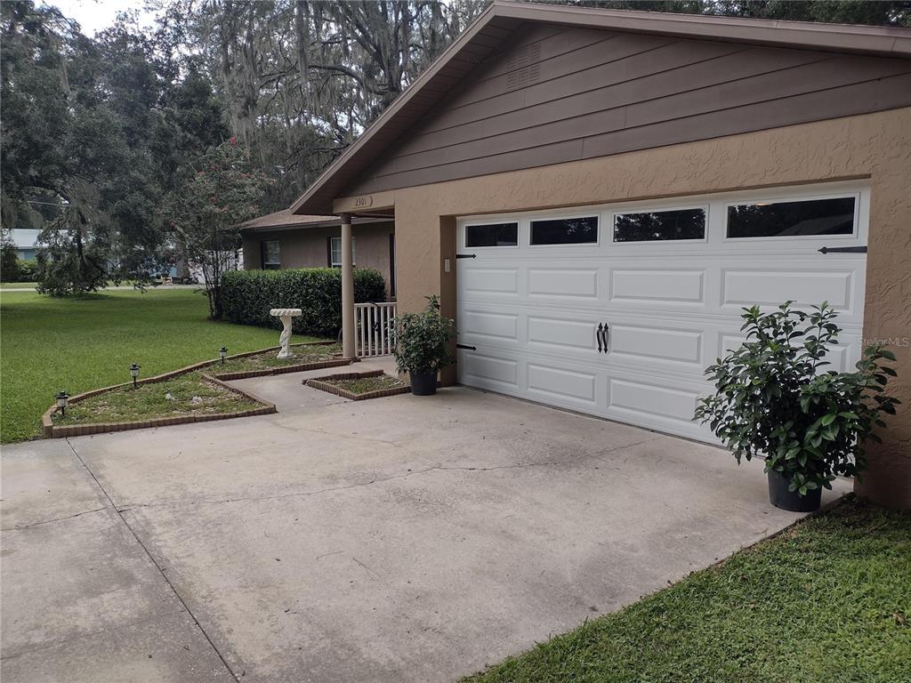 A concrete driveway leads to a white garage door and a covered front entryway — 2301 NE 32ND PLACE, OCALA, FL