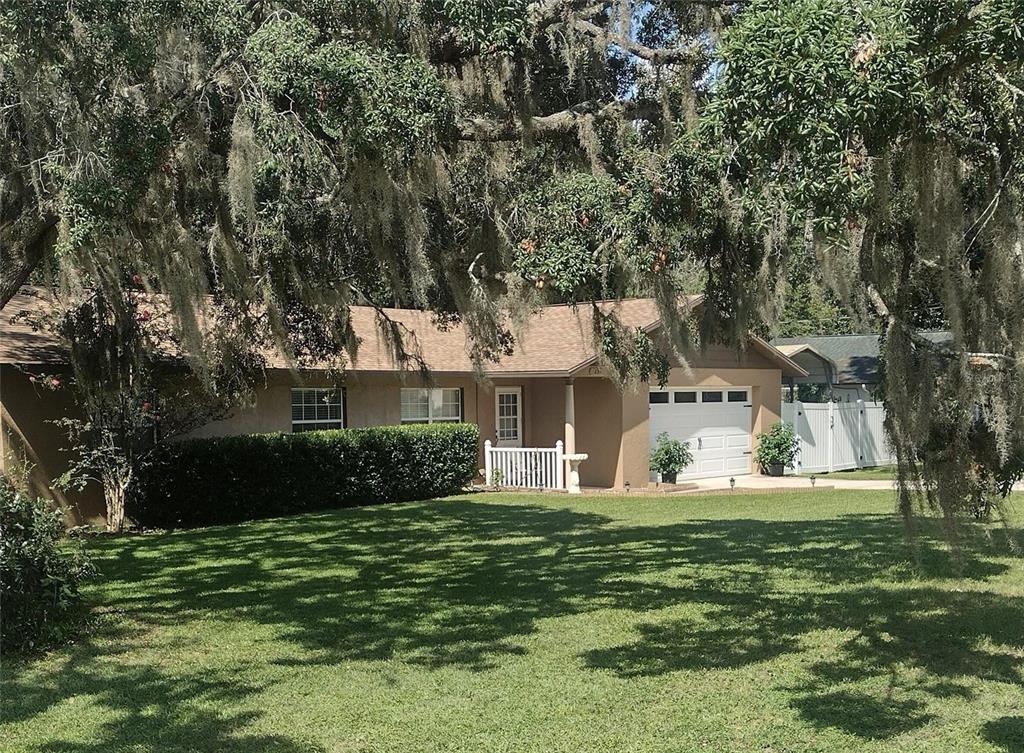 A single-story house with a tan exterior, white garage door, and a large front lawn — 2301 NE 32ND PLACE, OCALA, FL