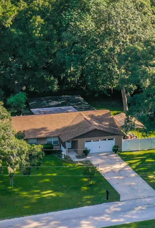 An aerial view shows a single-story house with a brown roof, garage, and screened pool enclosure — 2301 NE 32ND PLACE, OCALA, FL