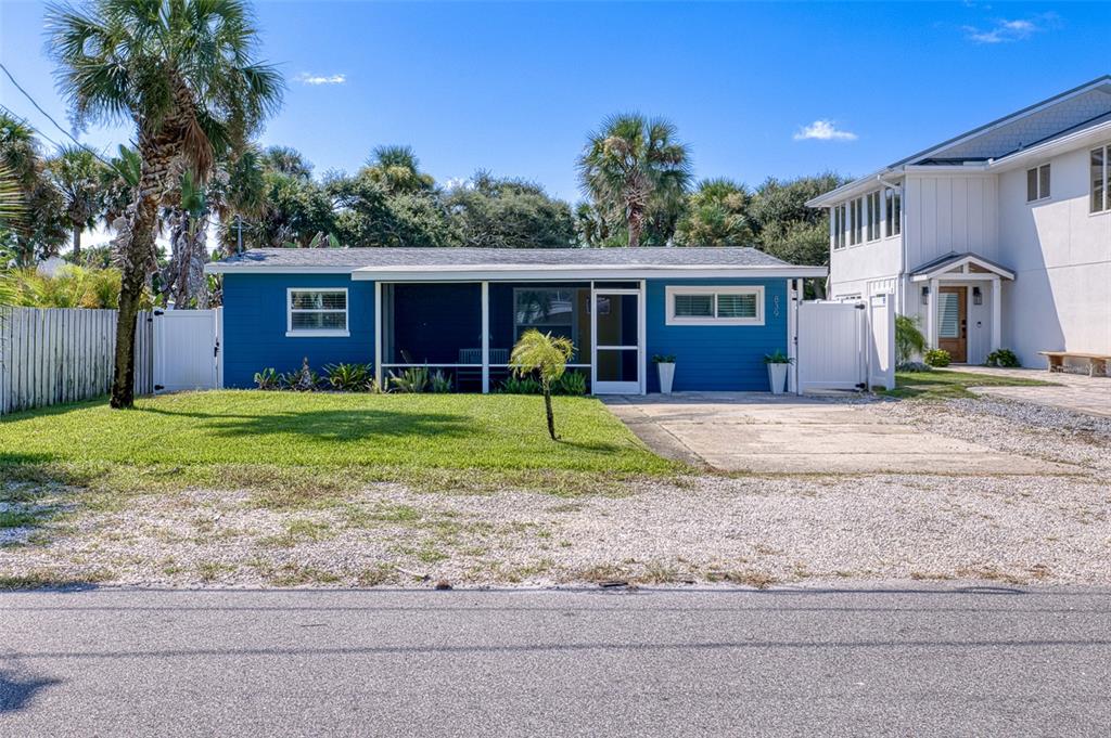 A blue single-story house features a screened front porch, a concrete driveway, and palm trees — 839 E 10TH AVENUE, NEW SMYRNA BEACH, FL