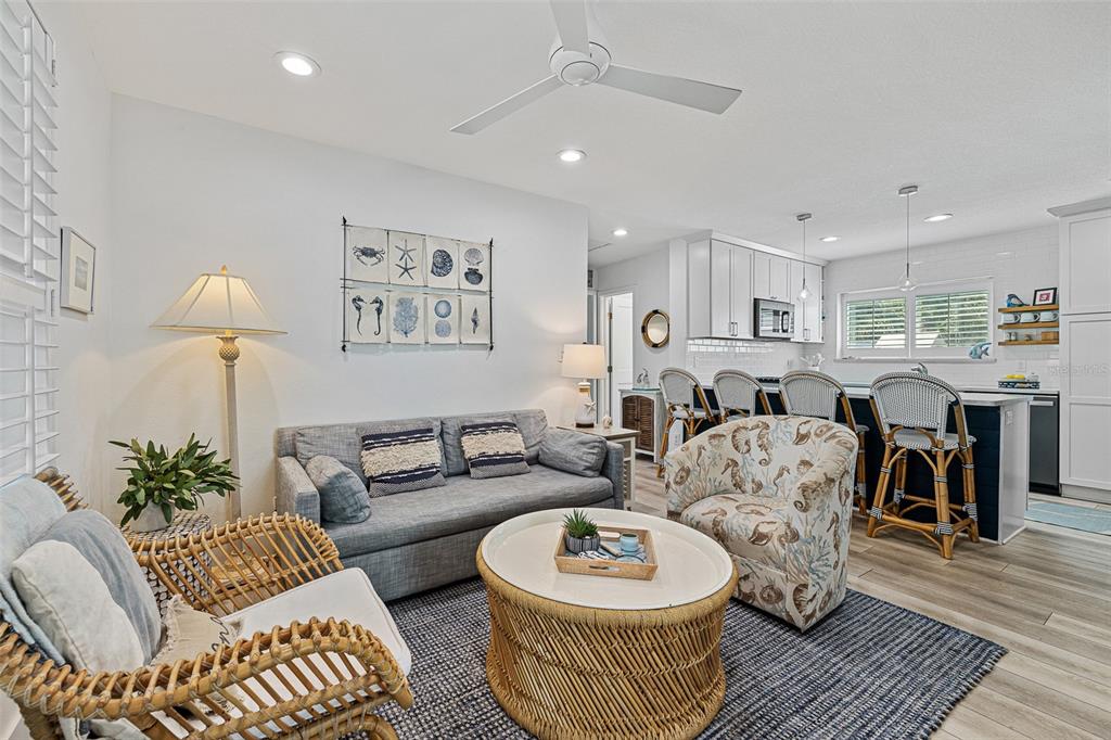A living room features a gray sofa, rattan furniture, and an open kitchen with bar stools — 839 E 10TH AVENUE, NEW SMYRNA BEACH, FL