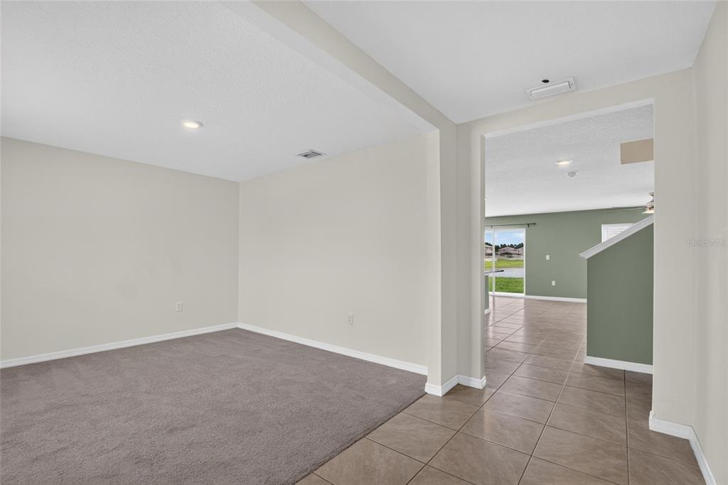 A carpeted room transitions into a tiled living area with a view of the outdoors — 2818 GUMBO LIMBO DRIVE, WIMAUMA, FL