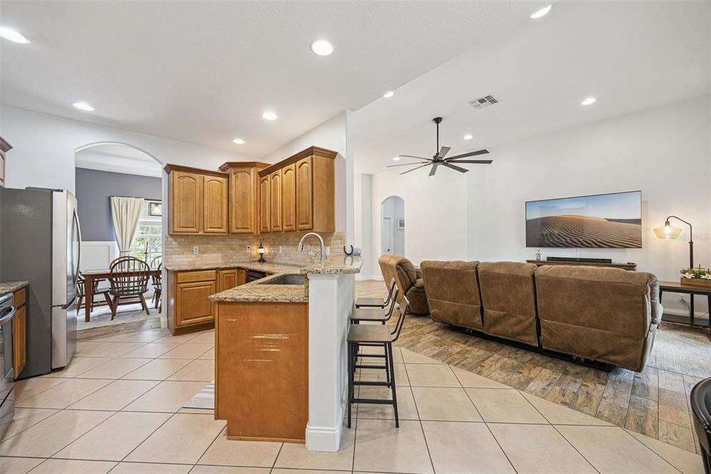 A living room features wood-look tile flooring, a ceiling fan, and a view of the backyard — 41220 ALDER WAY, EUSTIS, FL