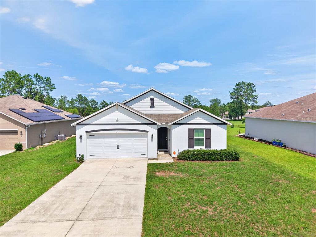 A single-story house with a white exterior, a two-car garage, and a front lawn — 55 HICKORY COURSE, OCALA, FL