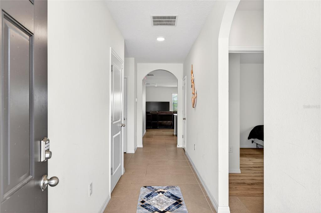 A tiled entryway leads through an arched hallway into a living area with wood flooring — 55 HICKORY COURSE, OCALA, FL