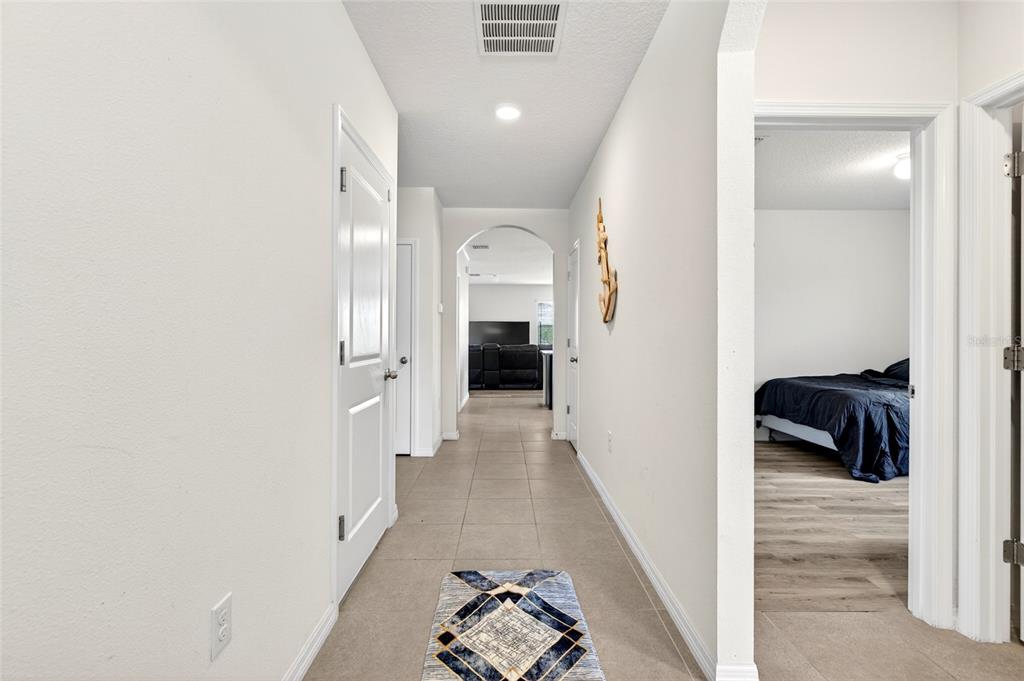 A hallway with tile floors leads past a bedroom doorway toward a living area — 55 HICKORY COURSE, OCALA, FL