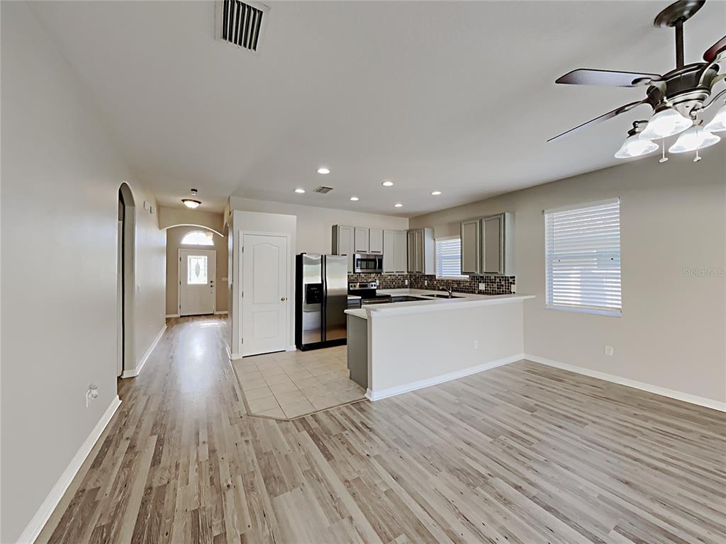 An open-concept kitchen with light gray cabinets and a breakfast bar overlooks a living area — 4020 LANGDRUM DRIVE, WESLEY CHAPEL, FL