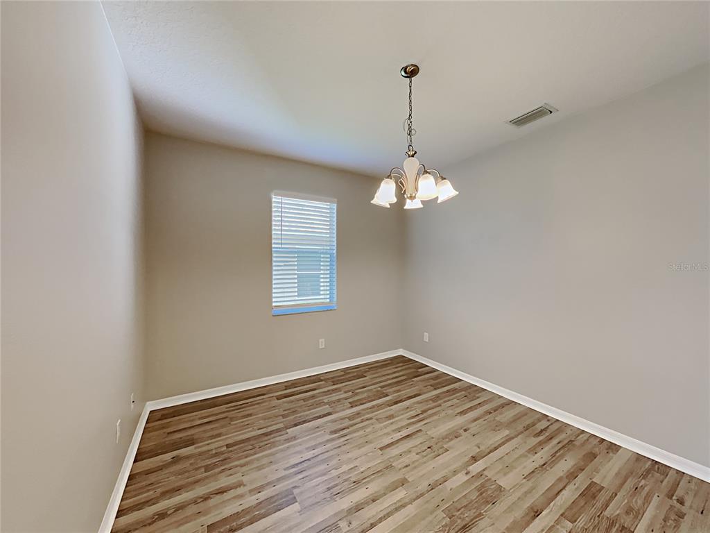 A dining room features light gray walls, wood-look flooring, and a multi-light chandelier — 4020 LANGDRUM DRIVE, WESLEY CHAPEL, FL