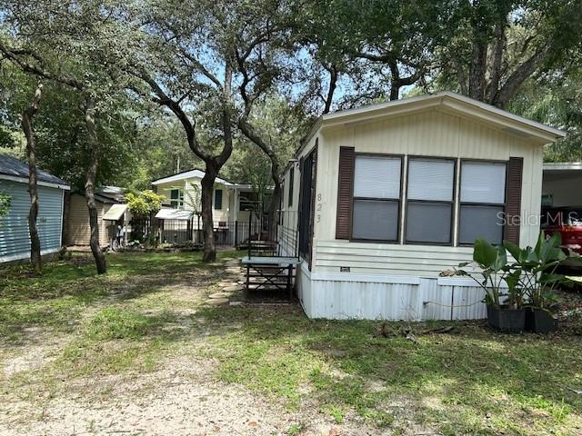 A light-colored mobile home sits on a grassy lot shaded by several large trees — 3000 CLARCONA ROAD UNIT 823, APOPKA, FL