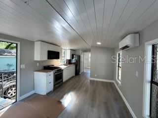 A small kitchen with white cabinets and light wood-look flooring opens into a living area — 3000 CLARCONA ROAD UNIT 823, APOPKA, FL