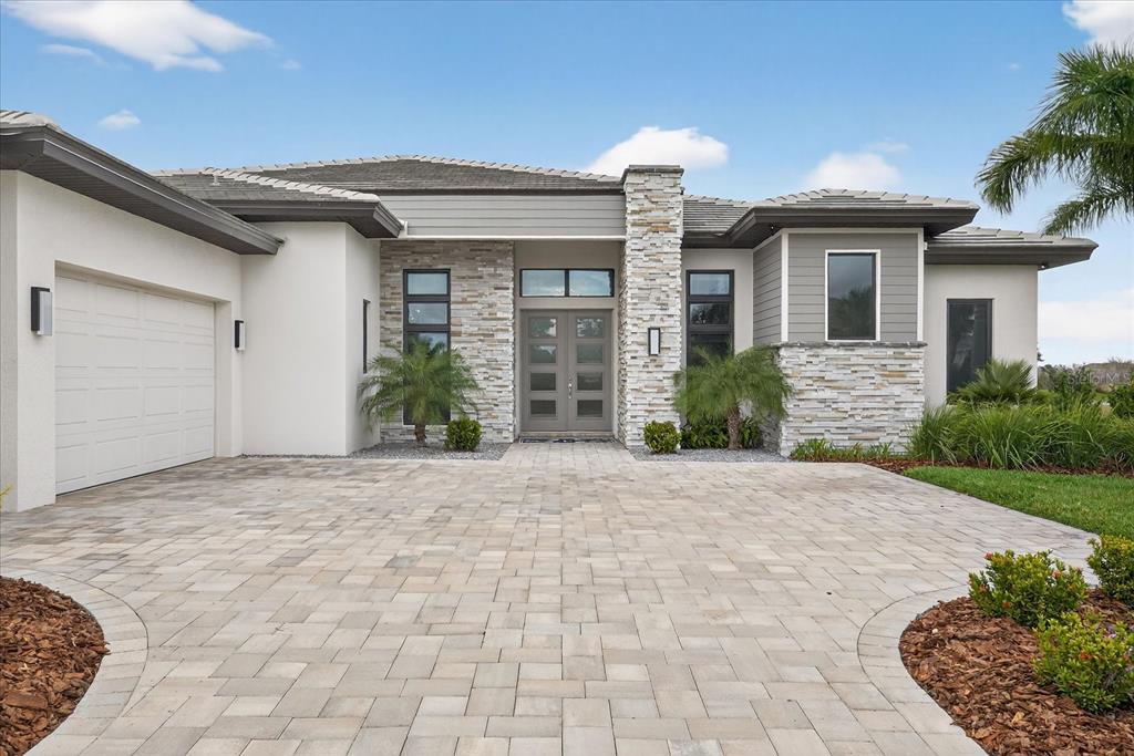 A modern single-story house features a stone facade, a paved driveway, and a palm tree — 4034 BUTTE TRAIL, BRADENTON, FL