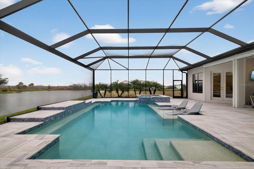 An aerial view of a house with a screened-in pool, patio, and tiled roof — 4034 BUTTE TRAIL, BRADENTON, FL