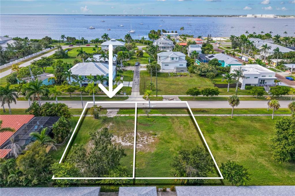 An aerial view shows two adjacent vacant residential lots bordered by a road and water — 821 W MARION AVENUE, PUNTA GORDA, FL