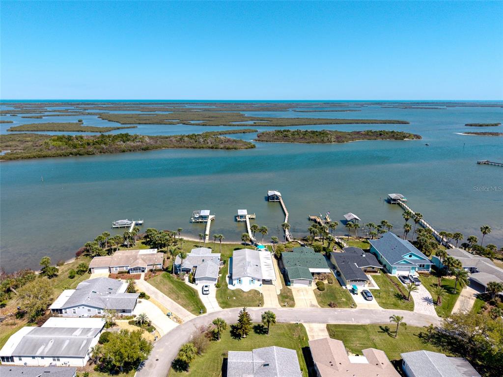 An aerial view shows waterfront houses with private docks along a bay with islands — 349 MARSH LANDING LOOP, OAK HILL, FL
