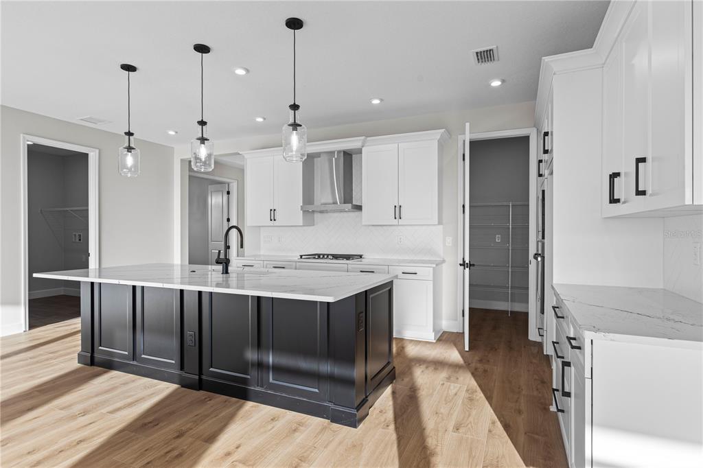 A kitchen features a dark island with a marble countertop and white perimeter cabinetry — 1617 BELLAGIO LOOP, TAVARES, FL