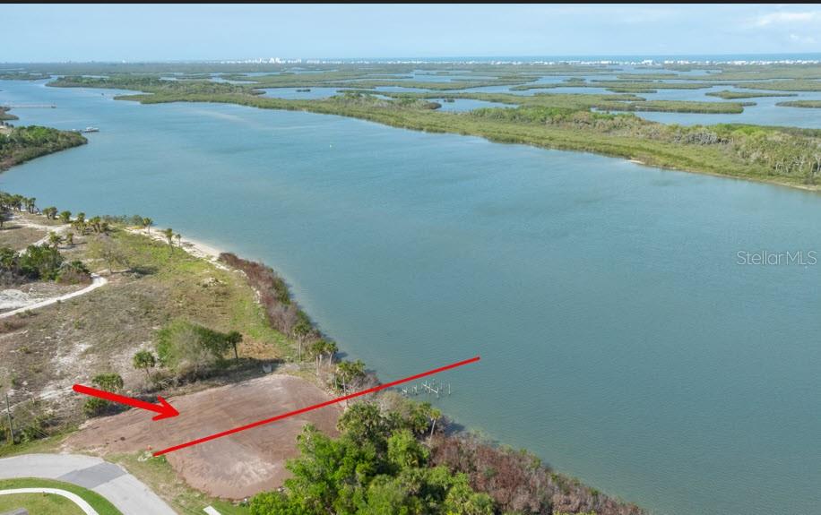 An aerial view shows a cleared waterfront lot with a red arrow pointing toward the property — 183 JONES FISH CAMP ROAD, EDGEWATER, FL