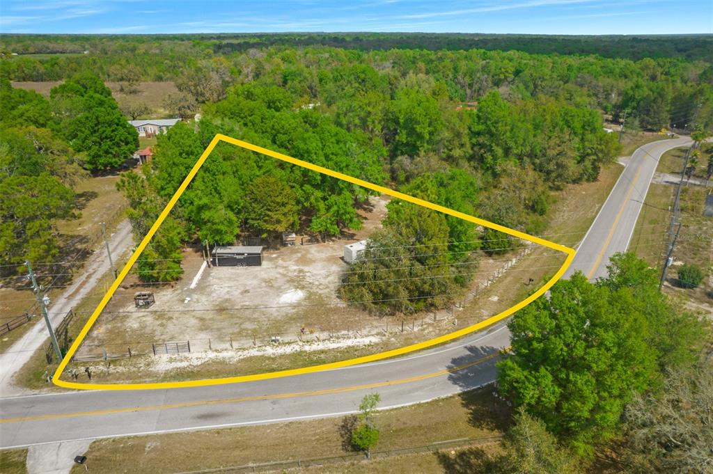 An aerial view shows a triangular plot of land with trees and two small structures — 17755 BOSLEY, SPRING HILL, FL