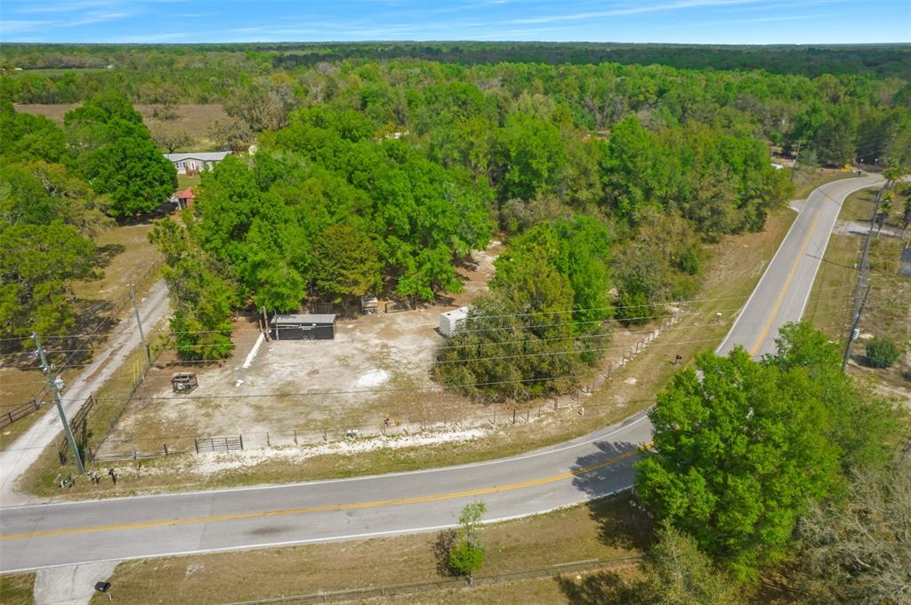 An aerial view shows a cleared, fenced lot with trees and two small structures — 17755 BOSLEY, SPRING HILL, FL
