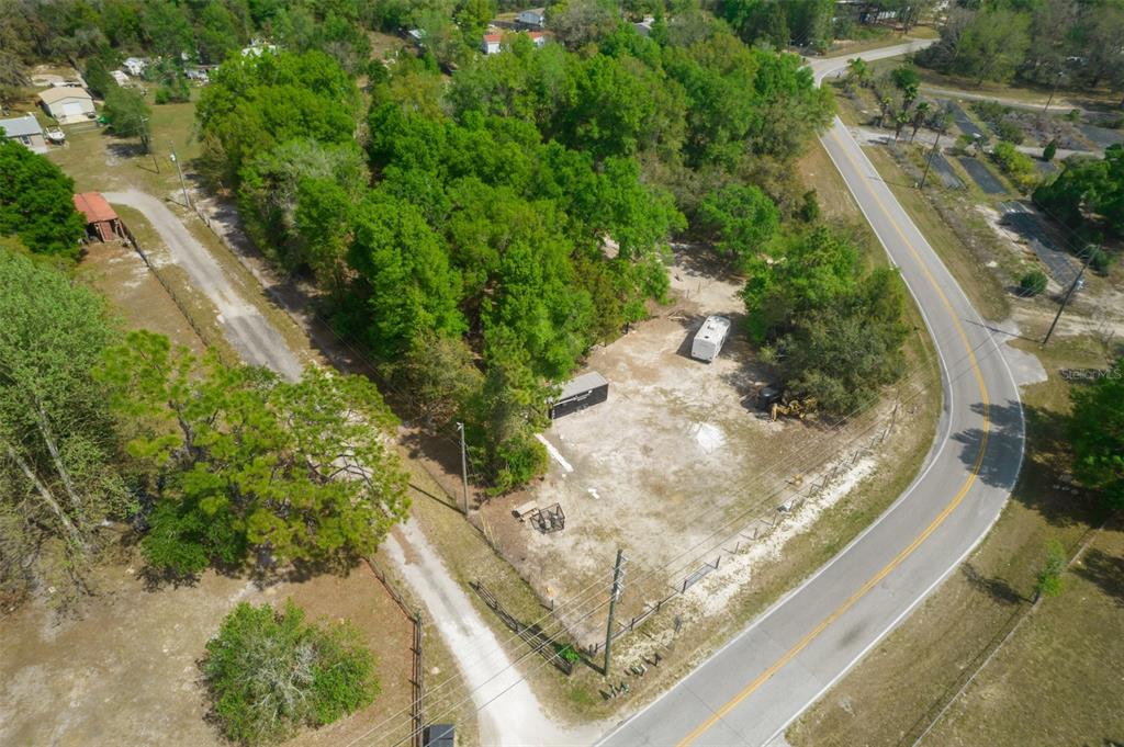 An aerial view shows a cleared, fenced lot with trees, a trailer, and a storage container — 17755 BOSLEY, SPRING HILL, FL