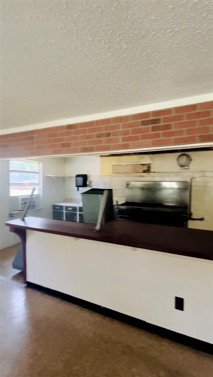 A kitchen features a long service counter, brick accent wall, and stainless steel equipment — 7103 N CARL G ROSE HIGHWAY, HERNANDO, FL