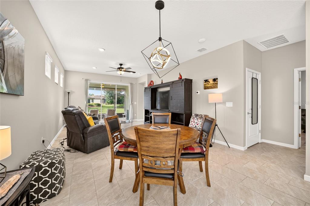 A dining area with a wooden table and chairs sits in front of a living space — 9664 SW 63RD LOOP, OCALA, FL