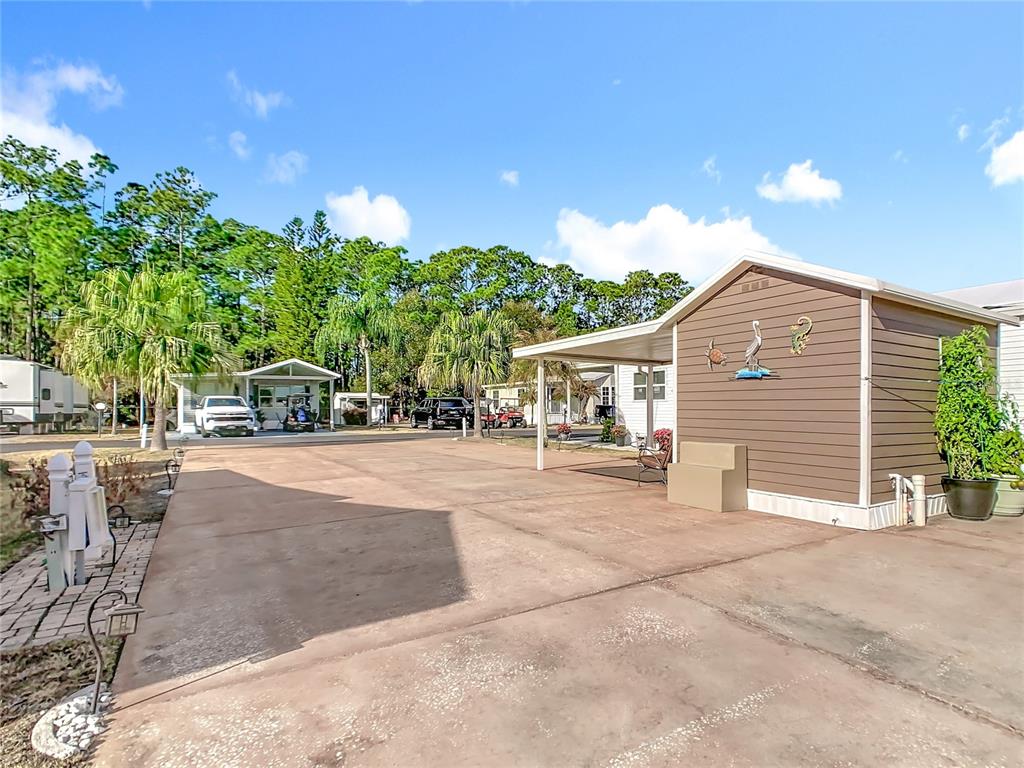 A paved driveway leads to a small brown shed with a covered patio area — 450 PINE LOOP, FROSTPROOF, FL