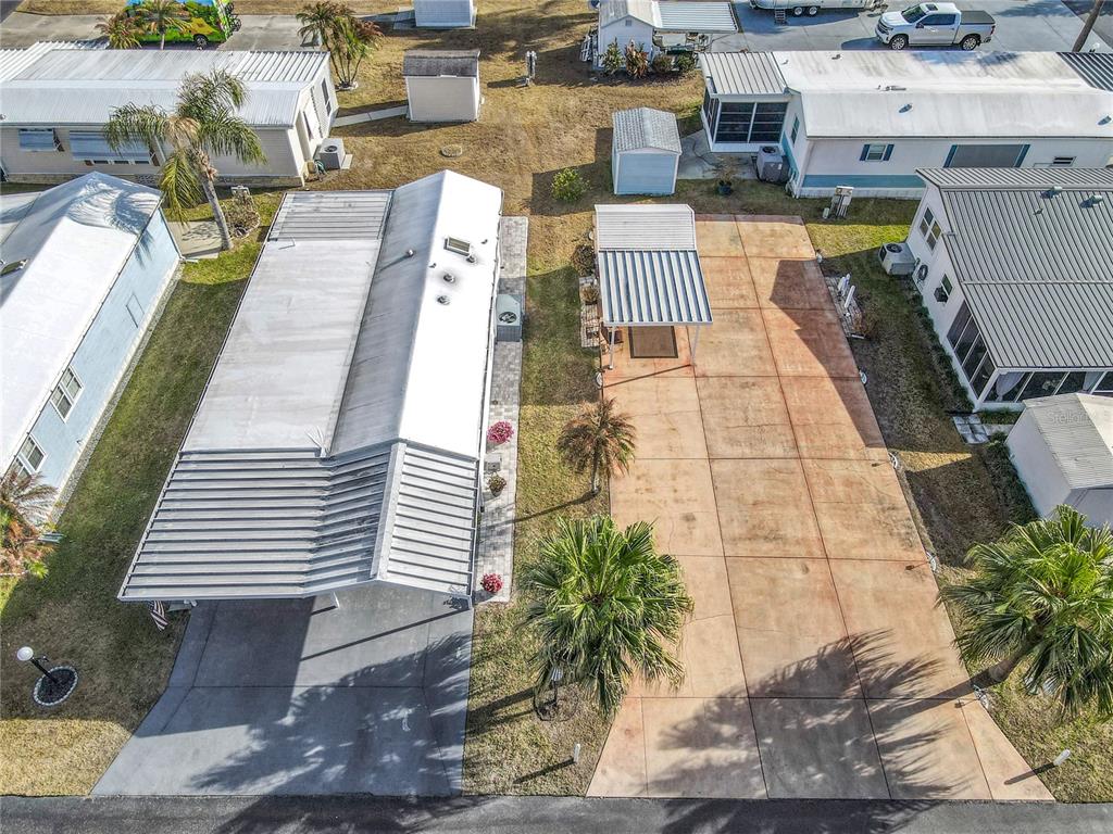 An aerial view shows two adjacent mobile homes with metal roofs, carports, and paved driveways — 450 PINE LOOP, FROSTPROOF, FL