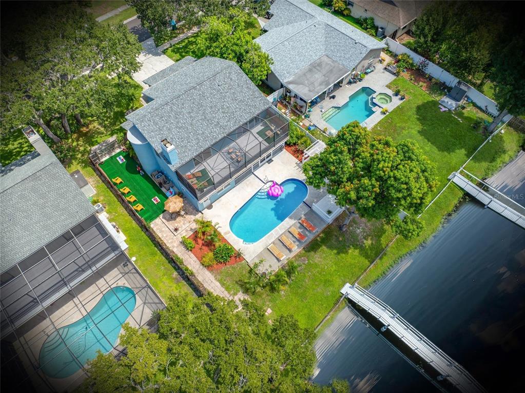 An aerial view shows three houses with swimming pools and a wooden dock on a canal — 2153 KARAN WAY, CLEARWATER, FL